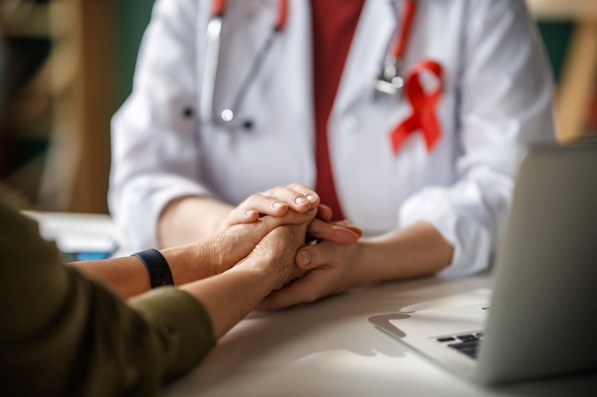Profesional de la salud sosteniendo con empatía las manos de una paciente
